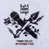 L'image présente un graffiti sur un mur. On y voit croisés un microphone et une plume, symbolisant la musique et l'écriture. Le nom "Tania Saleh" est inscrit en dessous, ainsi que le titre "INTERSECTION." Le design inclut également des éléments floraux qui embellissent la composition, ajoutant une touche artistique et expressive. Le tout est réalisé dans un style monochrome, ce qui accentue les détails des objets représentés.
