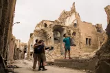 Ruines d'un bâtiment ancien, deux personnes explorent, l'atmosphère est sombre et désolée.