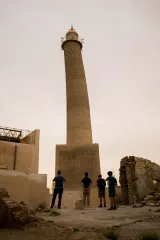 Un groupe de personnes admire un minaret élancé dans un paysage désertique.