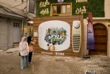 Deux enfants jouent devant une fresque murale colorée et une télévision vintage.