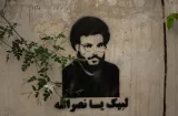 Graffiti d'un homme barbu sur un mur, avec des feuilles vertes en arrière-plan.