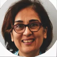 Femme souriante avec des lunettes, cheveux bruns et frisés, fond neutre.