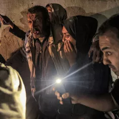 A group of people in a dim space, some worried, holding cell phone lights in tense expressions.