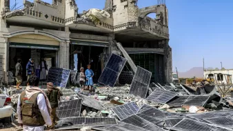 Destruction : bâtiment effondré, débris et panneaux solaires éparpillés autour.