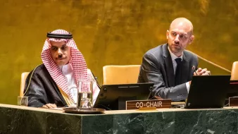 Deux hommes en costume assis à une table dans une salle de conférence.