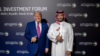 Deux hommes souriants, l'un en costume, l'autre en tenue traditionnelle, posent ensemble.