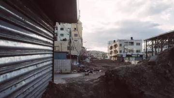 Strade deserte con edifici e terreni in costruzione, atmosfera grigia e cupa.