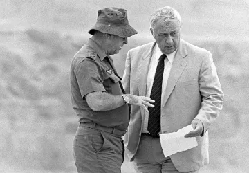 L'image montre deux hommes en train de discuter. L'un d'eux porte une tenue militaire, incluant un chapeau, tandis que l'autre est vêtu d'un costume clair. Ils semblent examiner un document ensemble et échanger des informations de manière sérieuse. L'arrière-plan est flou, suggérant un environnement extérieur. La scène dégage une impression de concentration et d'importance.
