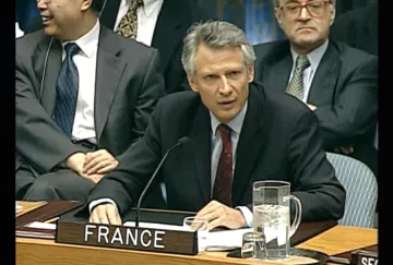Homme en costume, sérieux, représentant la France lors d'une réunion officielle.